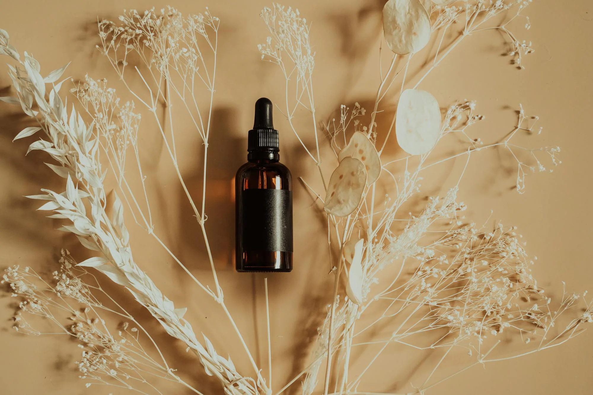 Flacon dropper botanique sur fond de plantes séchées - clean beauty