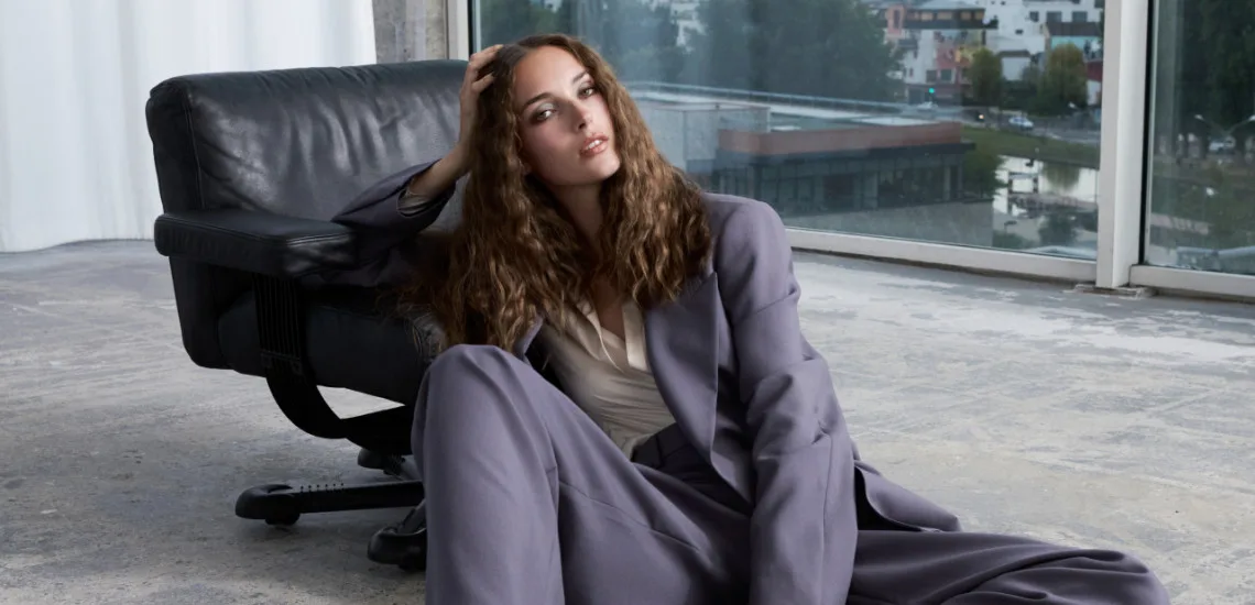 Cheveux bouclés lâchés et costume lavande, ambiance urbaine contemporaine, collection La Biosthétique PE 2026
